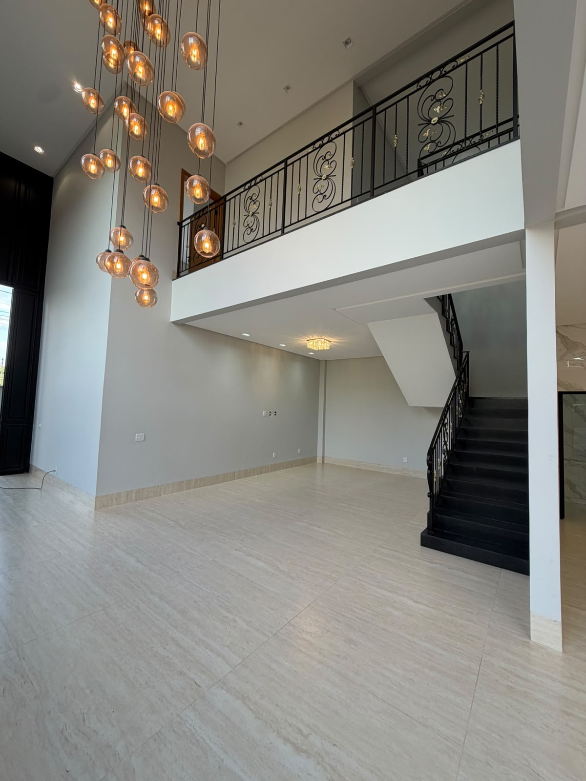 Sala de TV com pé-direito de 7 metros e lustre em cascata com 42 esferas de cristal